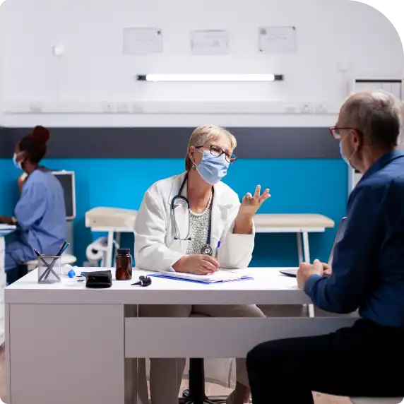 A doctor consults with a patient in a hospital room, discussing treatment options and health concerns.