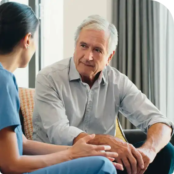 An aged man talking with a nurse.