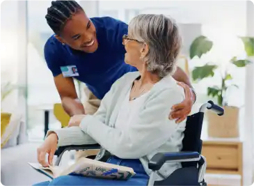 An old aged women on a wheelchair talking with a nurse.