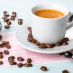 Stethoscope beside a cup of coffee, coffee beans, and a blood pressure monitor, representing the link between coffee and high blood pressure.
