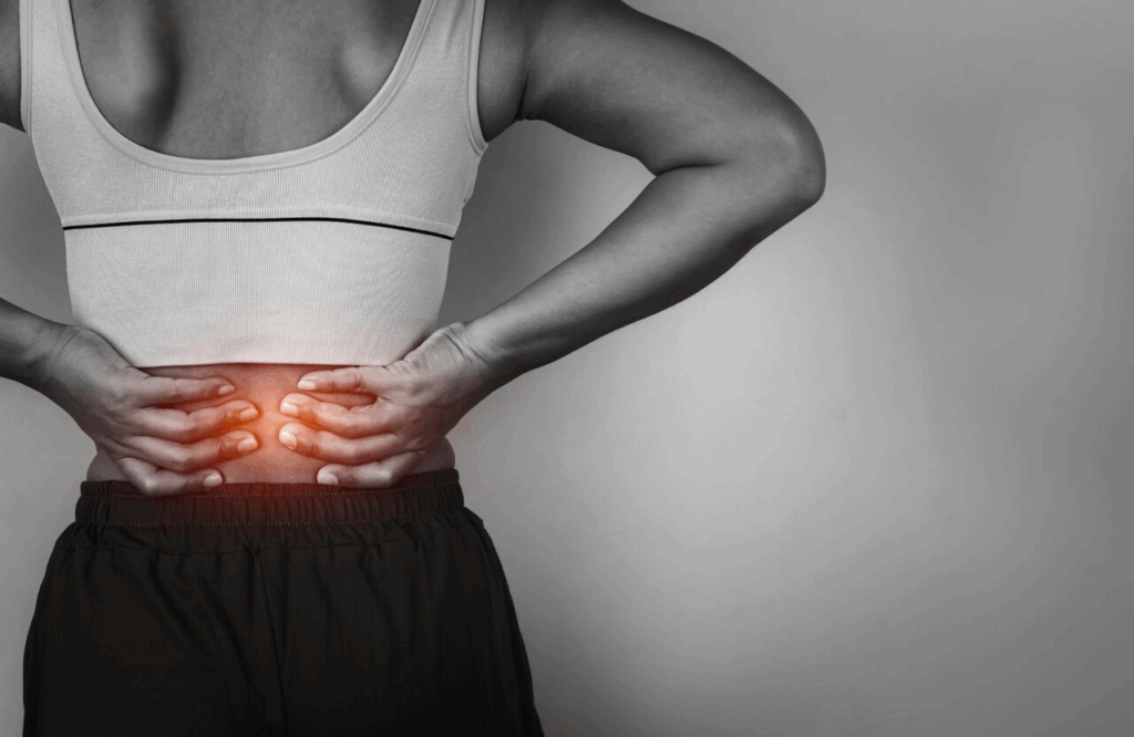 A person holding their lower back in pain, showing discomfort and strain, highlighting symptoms of back injuries.