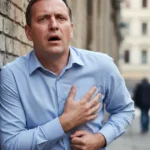 Man clutching chest while struggling to breathe on a street.