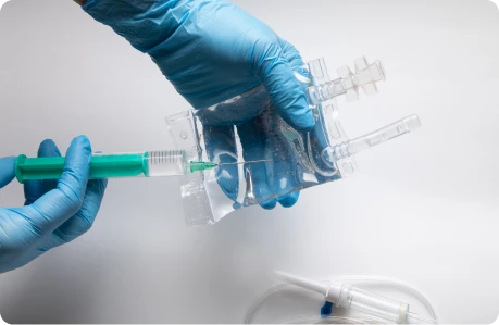 Gloved hands preparing a medical syringe and tubing.