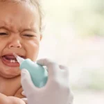 Baby crying while having nasal suction during teething.