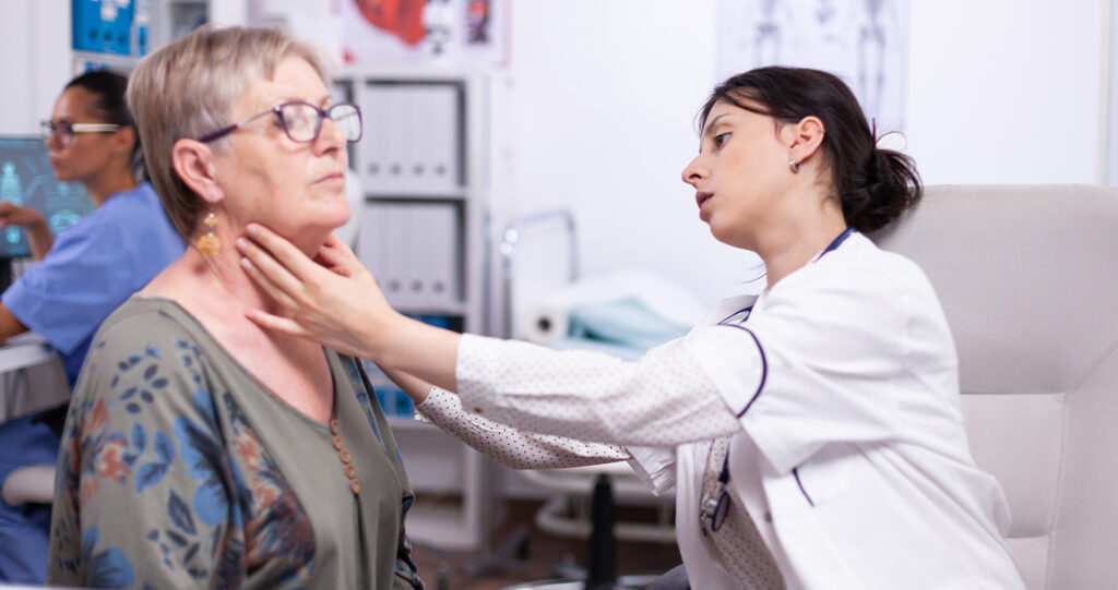 A doctor performing a physical neck examination on an elderly female patient.