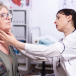 A doctor performing a physical neck examination on an elderly female patient.