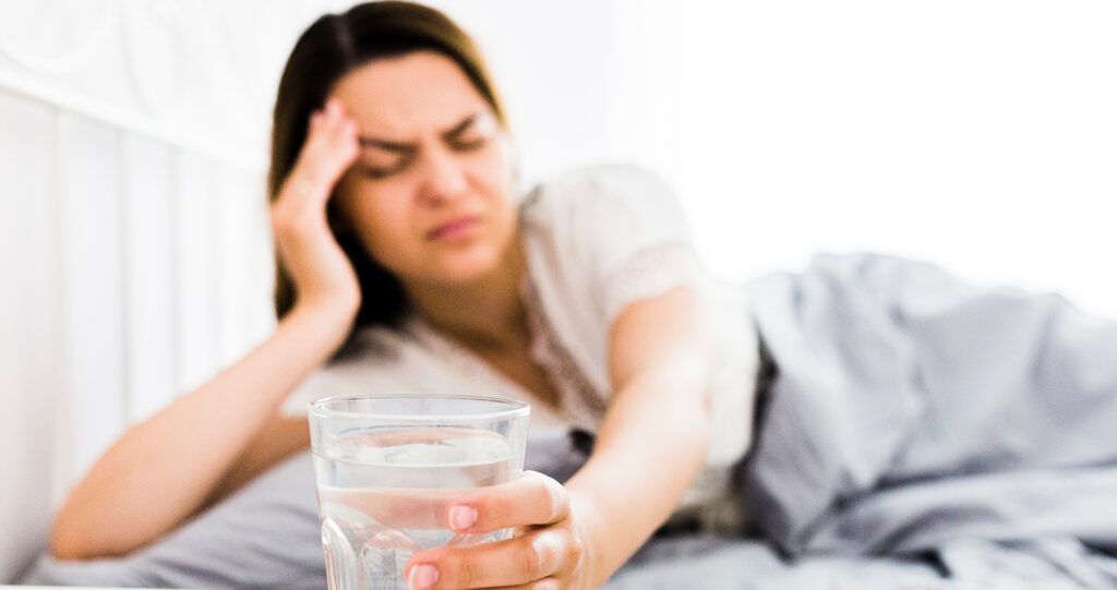Blurred woman in bed reaching for a glass of water