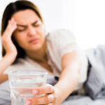 Blurred woman in bed reaching for a glass of water