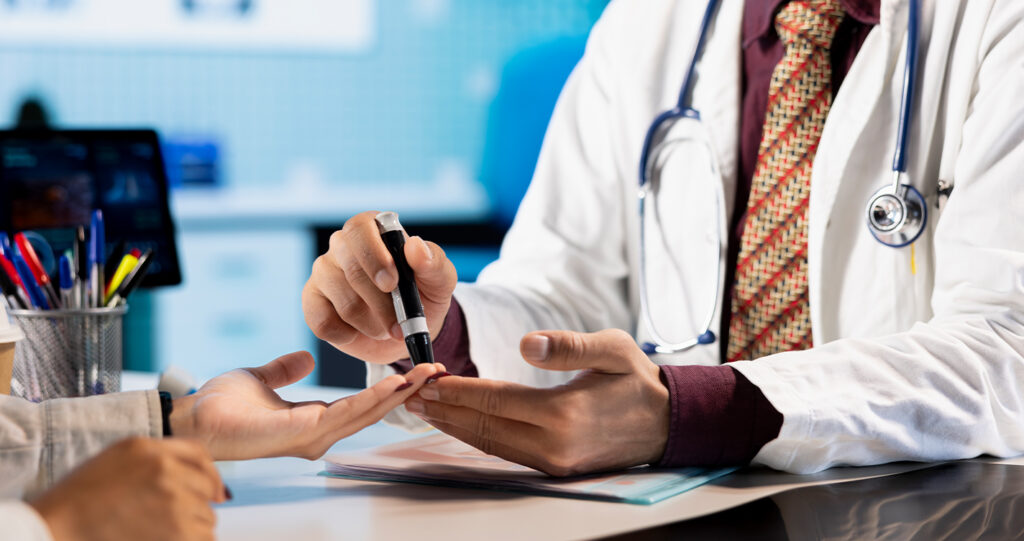 Doctor using a lancing device on a patient's finger.
