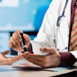 Doctor using a lancing device on a patient's finger.
