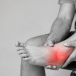Person holding a painful swollen ankle with red injury highlight.