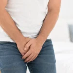 A man holding his groin while experiencing urinary discomfort.