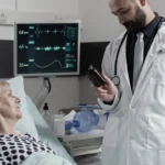 Doctor showing a medicine bottle to a patient lying in bed.