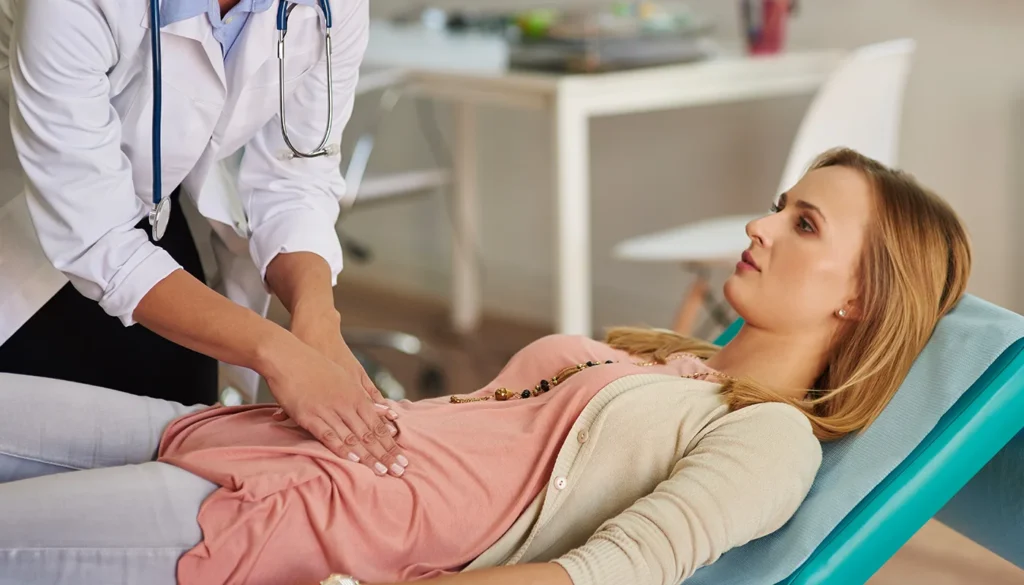 Doctor examining a female patient's abdomen in a clinic setting.
